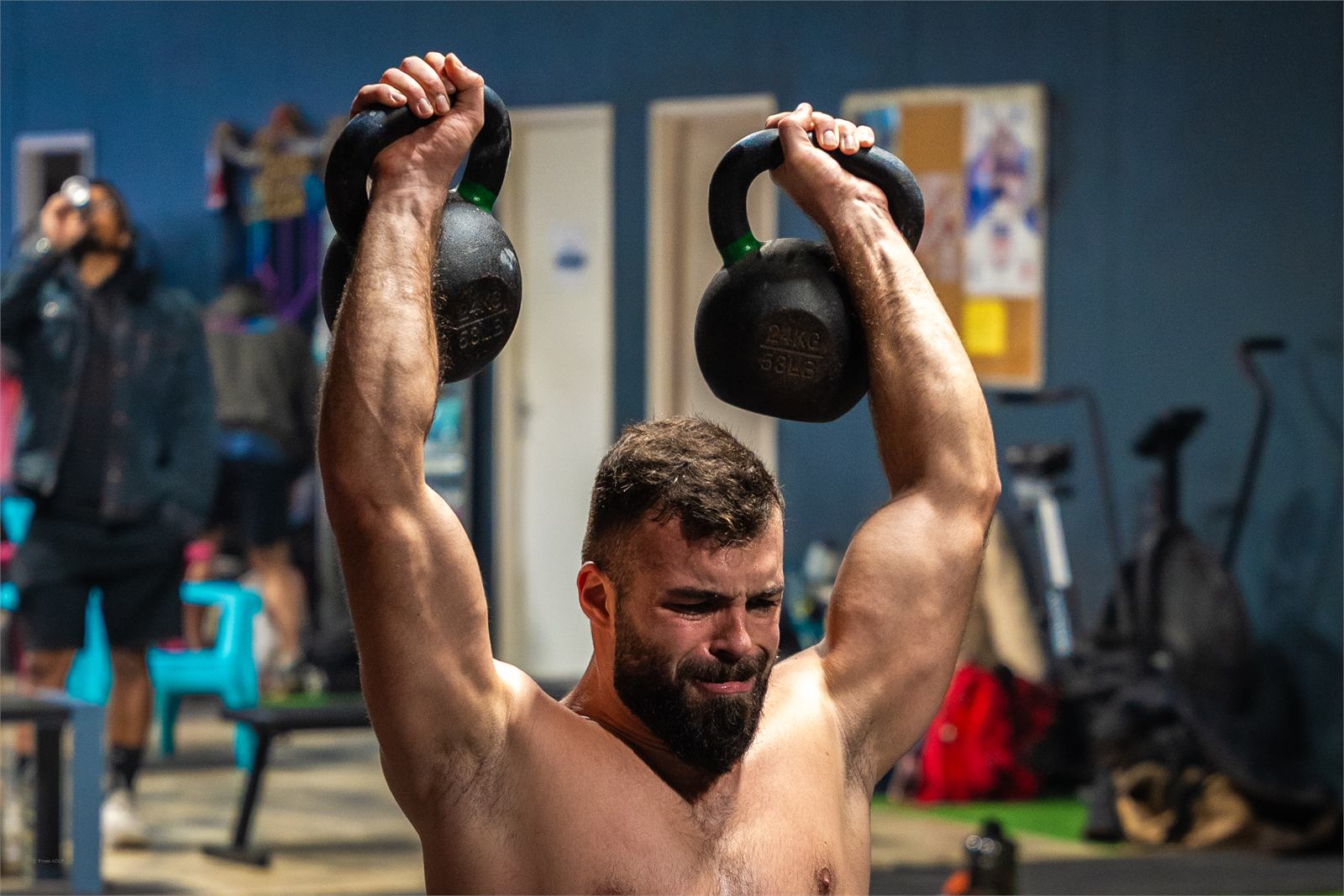 Athlète avec deux kettlebells au-dessus de la tête